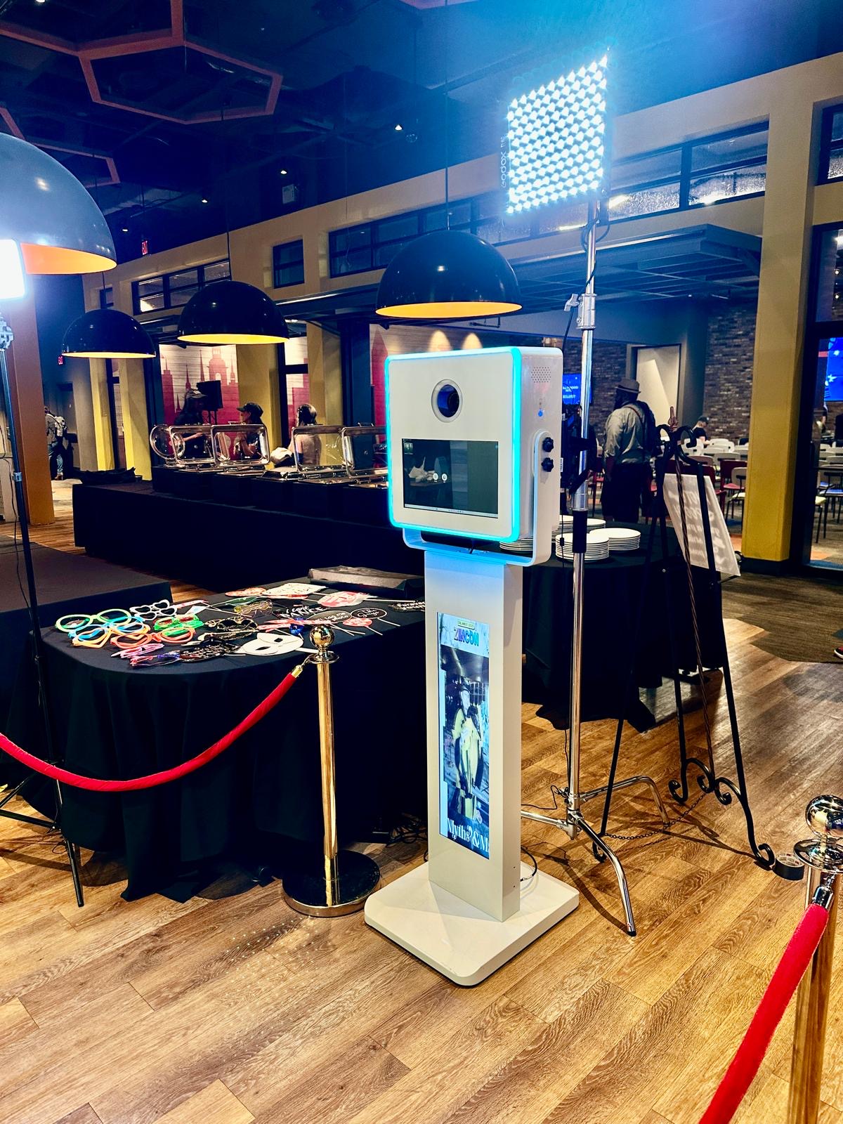 M'S 360 photo booth kiosk with studio lighting, props table and red rope at an Orlando venue