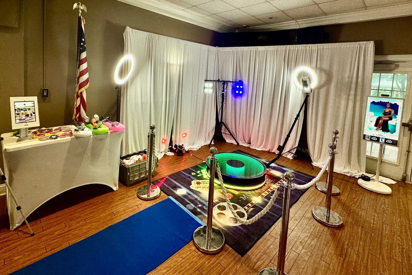 360 photo booth platform with LED ring lights, props table and stanchions at an Orlando event